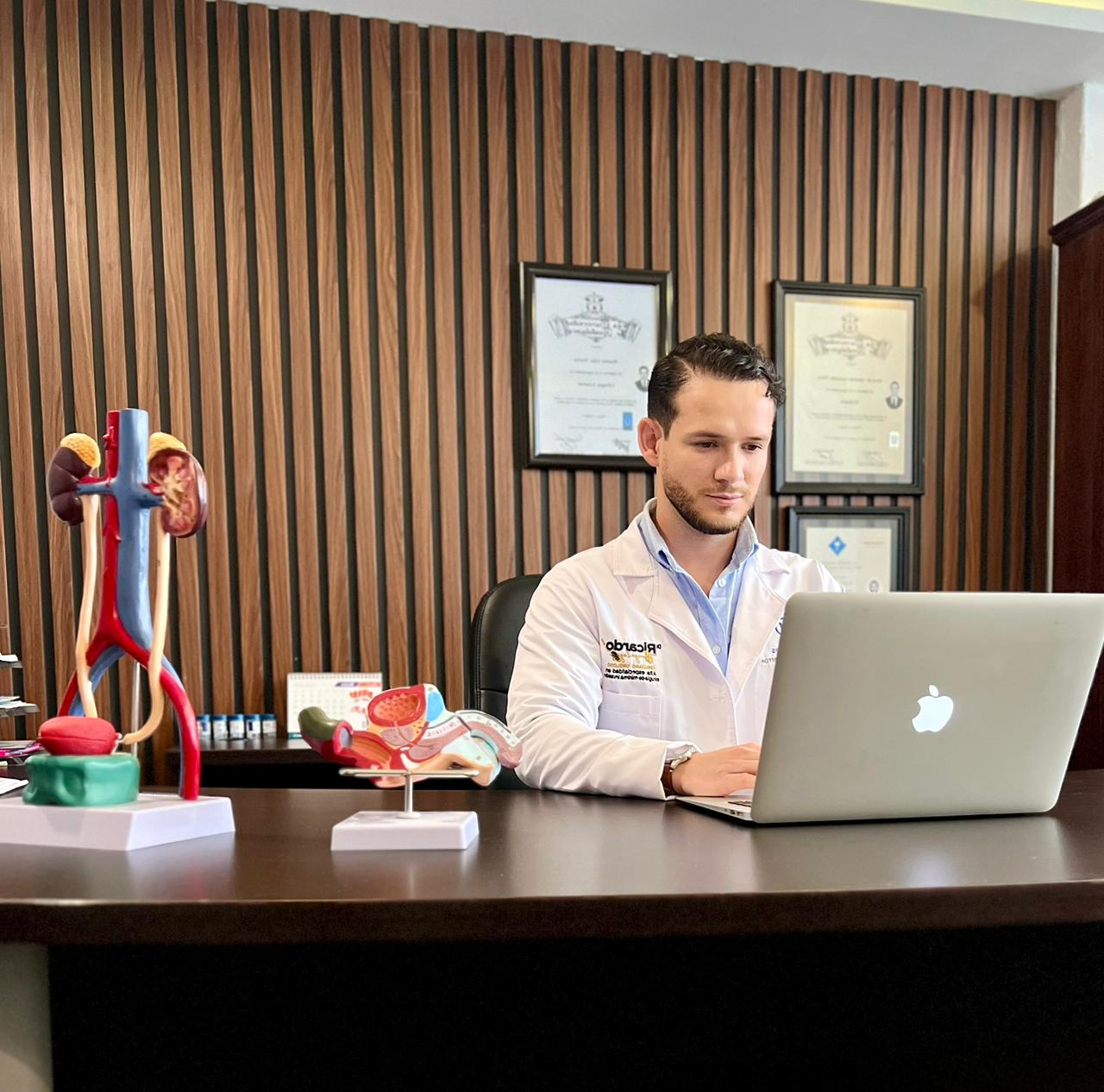 Dr. Ricardo González atendiendo en su consultorio, junto a modelos anatómicos